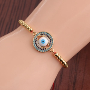 Close-up of evil eye gold bead bracelet with blue and white zircon stones on model