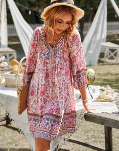 Gros plan d'une robe bohème rose à fleurs, col en V et manches longues en plein air ensoleillé