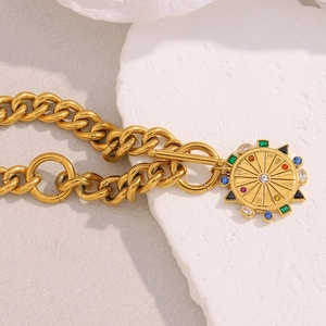 Détail macro du collier chaîne cubaine plaqué or 18 carats avec pendentif boussole et pierres fines