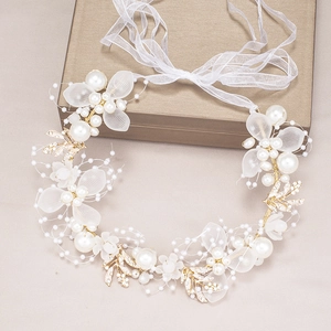 Detail of floral bridal headband with white pearls and gold wire on a gift box