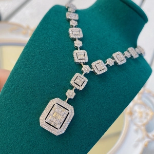 Close-up of luxury silver-tone emerald-cut zircon necklace on a green velvet mannequin