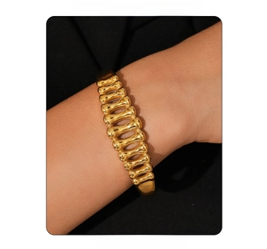 Close-up of gold-plated fishbone linkage bracelet worn by model on minimalist background