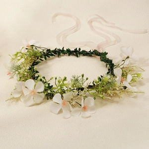Detailed view of white floral wreath crown with pink stamens and adjustable ribbons