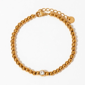 Vue macro du bracelet à billes dorées avec cristal central et fermoir mousqueton réglable
