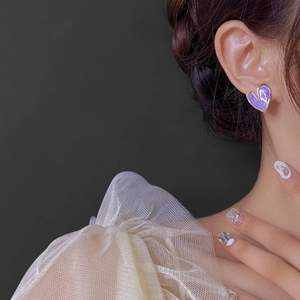 Détail d'une boucle d'oreille cœur en émail violet marbré avec bordure dorée