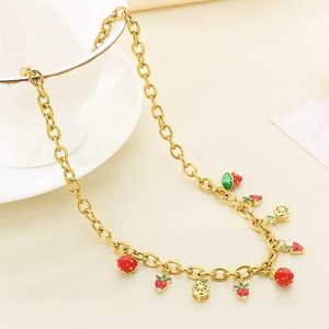 Collier doré avec pendentifs fraise et cœur sur un fond de tissu beige élégant