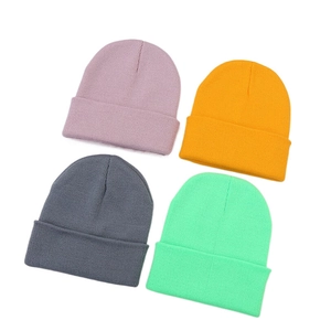 Posa piatta di quattro berretti in maglia colorati in viola, arancione, grigio e menta