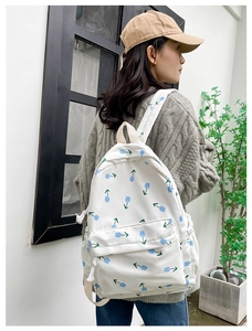 Floral nylon backpack with blue tulip patterns and front zip pocket on a female model