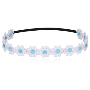 Detail of white embroidered daisy flowers with blue centers on a soft elastic baby headband