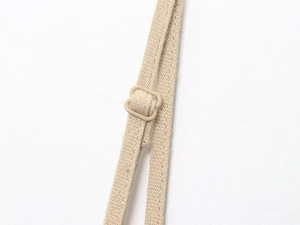 Détail macro de la bretelle en tissu beige ajustable avec boucle en plastique sur robe midi