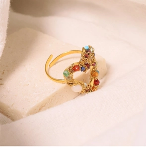 Close-up of golden heart-shaped ring with colorful beads on a natural stone background