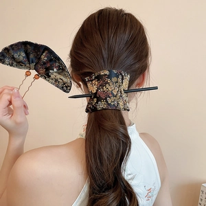 Detail of embroidered floral hair pin and black fabric hair wrap for traditional styling