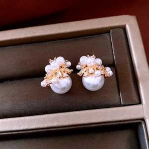 Detailed macro view of 18K gold plated pearl stud earrings with zircon floral accents
