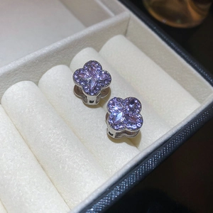 Macro shot of clover earrings with marquise purple stones in a white velvet box