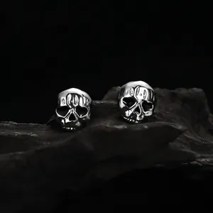 Gothic skull stud earrings with dark vintage finish on black stone background