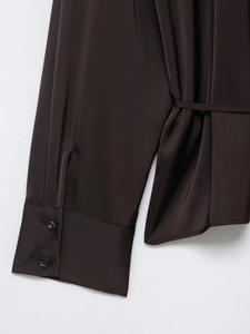Detailed view of the dark satin shirt sleeves with double buttons and waist tie closure