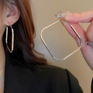 Macro shot of silver geometric square hoop earrings with polished metal buckle detail
