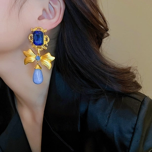 Detail view of vintage bow earrings with blue waterdrop pendants on a female model