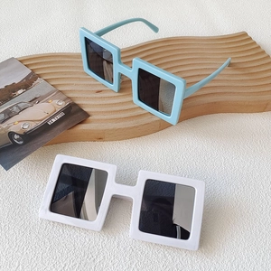 Close-up of light blue and white square sunglasses on a wooden tray with retro accents