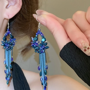 Detailed close-up of blue crystal flower tassel earrings worn by a model in soft light