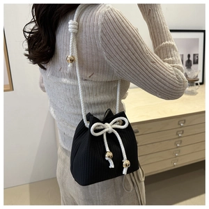 Dettaglio borsa a secchiello nera con coulisse, tracolla in cotone bianco e perline oro