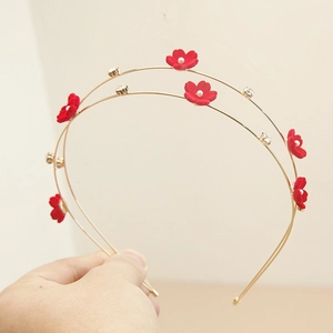 Detail of a double-layered golden headband with red velvet flowers and white pearls