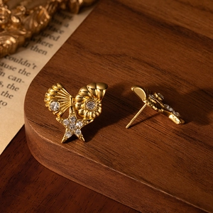 Golden titanium steel shell star earrings with rhinestones on vintage wooden background