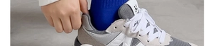Dettaglio di scarpe da corsa in mesh grigio e camoscio con calzini blu scuro