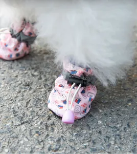 Macro detail of a pink pet shoe on a dog with cartoon cat print and drawstring buckle