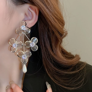 Detail view of silver flower earrings with zircons and pearl pendant on a model