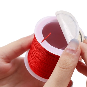 Macro shot of a red 0.8mm polyester cord spool with a hand removing the seal sticker