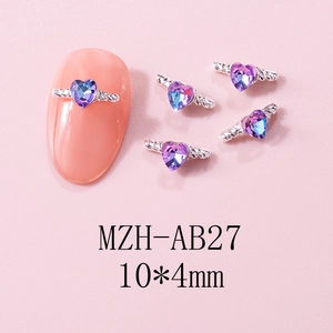 Macro view of silver angel wing nail charms with iridescent heart-shaped blue-purple gems