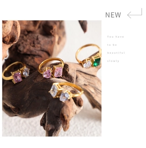 Detailed close-up of gold plated rings with colorful gemstones on natural wood stand