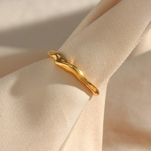 Macro shot of gold irregular bamboo style ring on elegant beige silk fabric texture