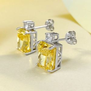 Macro shot of silver stud earrings featuring rectangular yellow stone and white round zircon