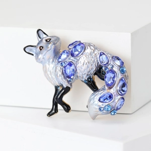 Detailed view of fox brooch with blue gemstone on a white geometric display stand