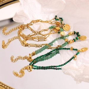 Detail of 18K gold-plated stainless steel layered bracelet with malachite beads and coin charm