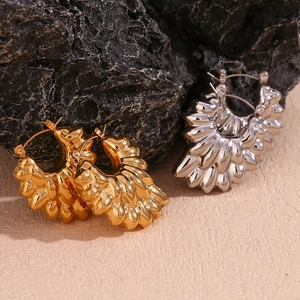 Detailed shot of gold and silver hollow double petal earrings on dark volcanic rock
