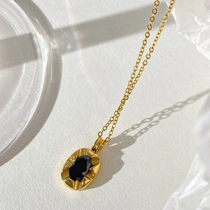 Gold stainless steel necklace with black oval gemstone pendant and radial vintage texture