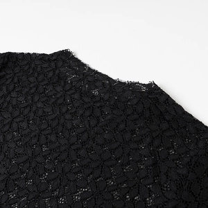 Dettaglio macro del tessuto in pizzo floreale nero con trama traforata elegante