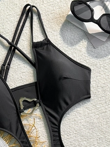Detail of black cut-out swimsuit featuring a silver heart-shaped metal buckle and straps