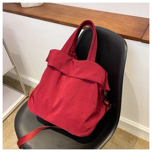 Detail of red nylon tote bag with adjustable shoulder strap on a black chair