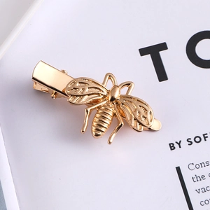 Macro shot of a golden bee hair clip with detailed hollow wings on a magazine page