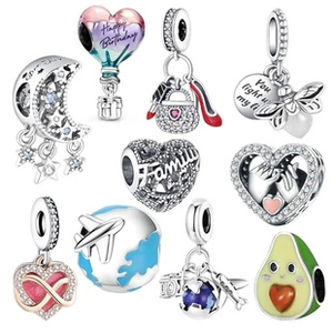 Macro shot of silver metal beads with colorful enamel and zircon charms on white backdrop