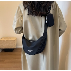 Dettaglio della borsa a tracolla in nylon nero con portamonete su un trench coat