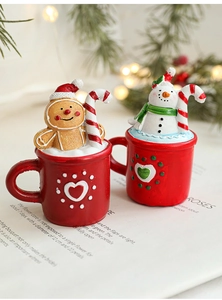 Macro detail of resin Christmas figurines snowman and gingerbread man in red mugs