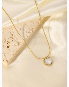Detail of gold heart pendant with white shell inlay on elegant silk background