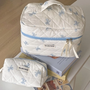 Dettaglio di beauty case trapuntati bianchi con decorazioni a fiocco blu vintage