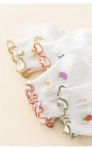 Detail of white cotton mesh socks for babies with ruffled cuffs and cartoon prints