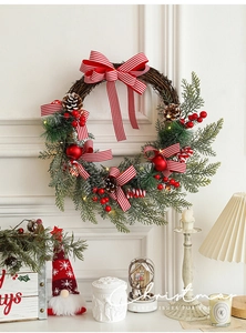 Close-up of Christmas wreath with red berries, pine cones and LED lights on white wall